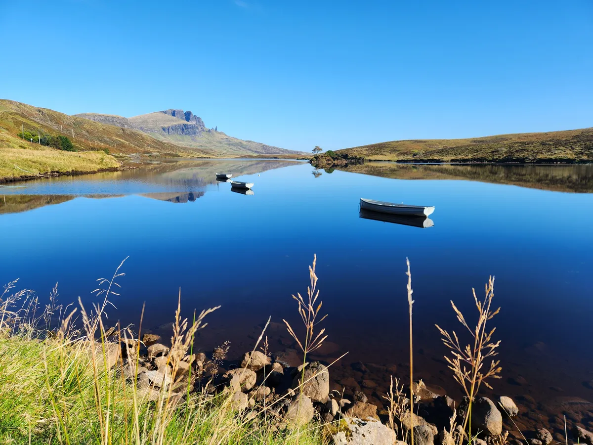 Scottish loch at golden hour with boats and mountain backdrop